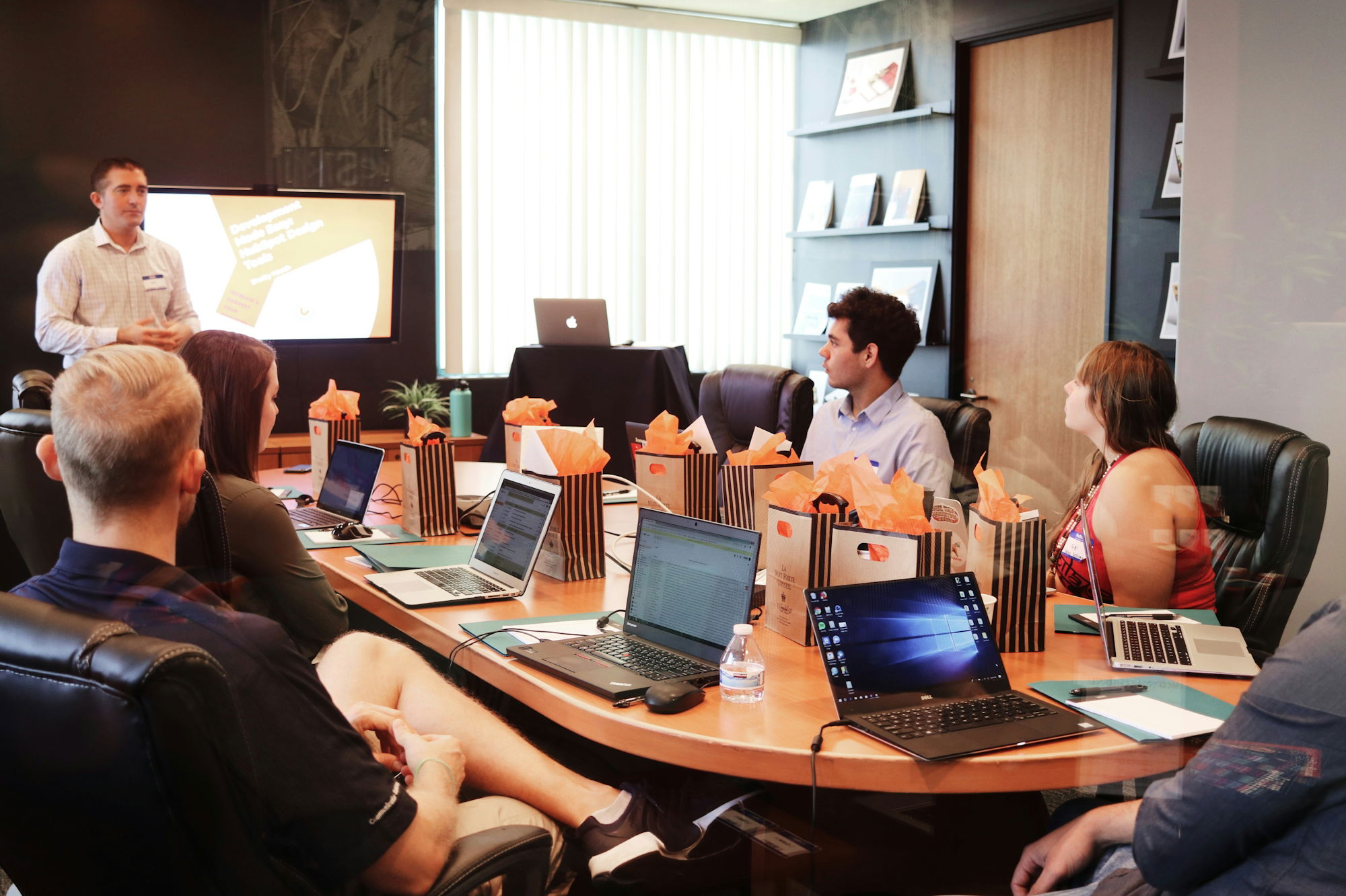man-standing-in-front-of-people-sitting-beside-table-with-laptop-computers.jpg man standing in front of people sitting beside table with laptop computers